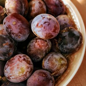 A detailed close-up of ripe plums in a bowl, showcasing their fresh and nutritious appeal.