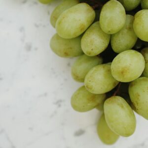 Close-up of fresh green grapes on a white marble background, perfect for healthy food concepts.
